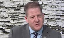 NH Gov. Chris Sununu with chipped lead paint in the background