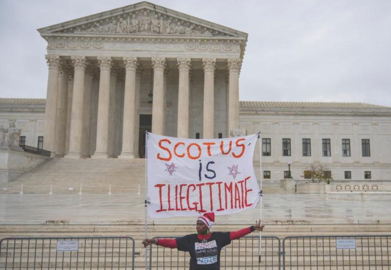 Protester in front of the Supreme Court with sign that reads "SCOTUS is Illigitimate"